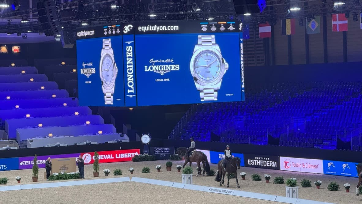 Carrière de dressage de Longines Equita Lyon, éclairée en bleu, avec l’écran géant Longines au-dessus des tribunes
