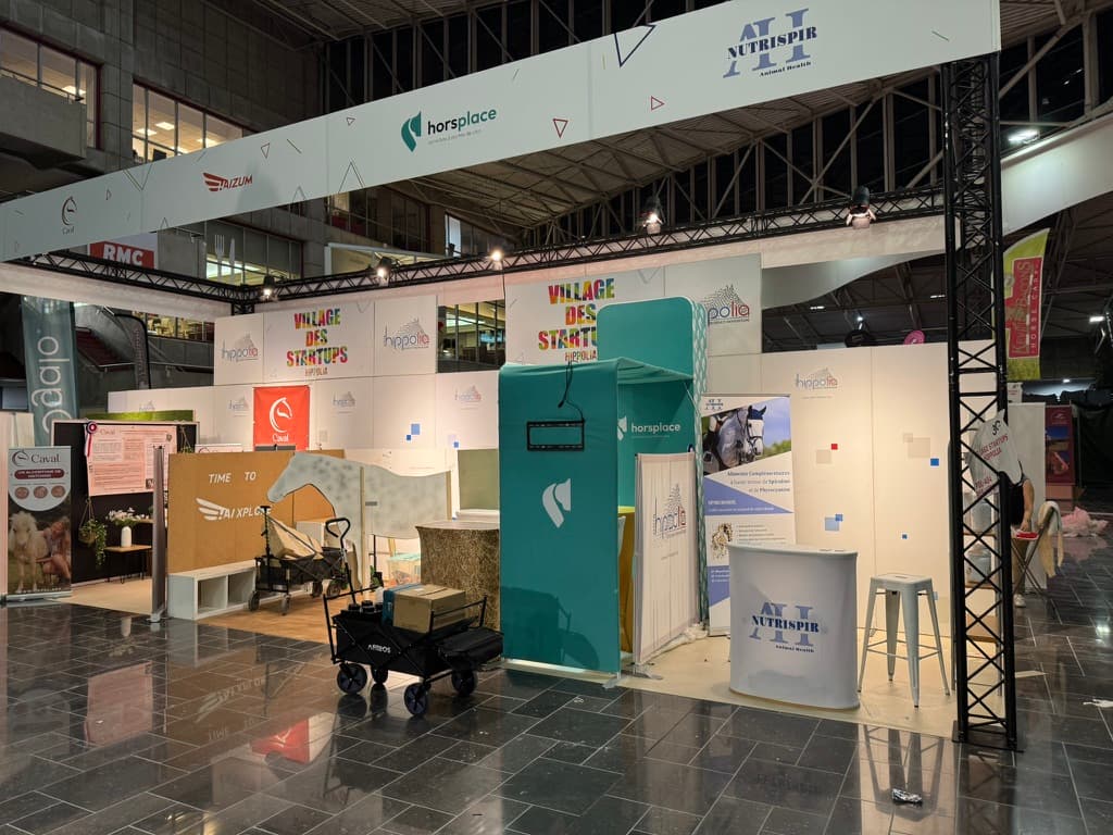 Stand Horsplace au Village des start-up Hippolia à Equita Lyon : colonne vert d’eau avec support d’écran, botte de paille et bannière Horsplace au-dessus des stands